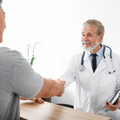 Happy doctor shaking hands with patient in hospital