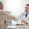 doctor shaking hands with his mature patient over the table